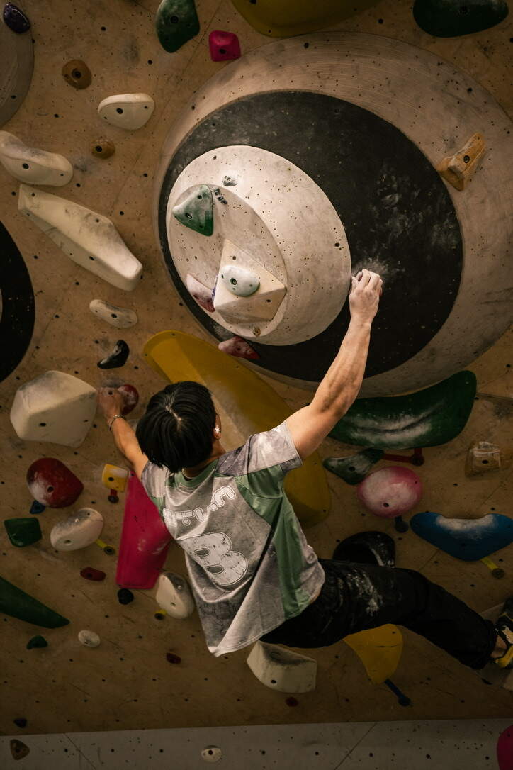 Climber reaching across the disc mural wall