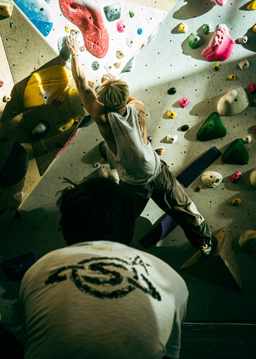 Two climbers helping each other over the top