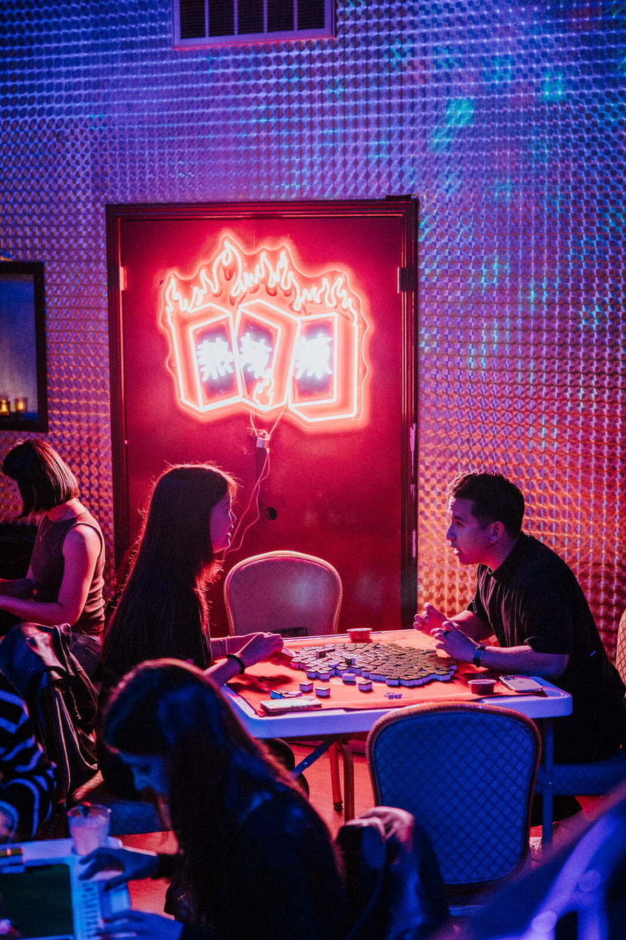 Neon mahjong sign over the tables at Paper Tiger Bar